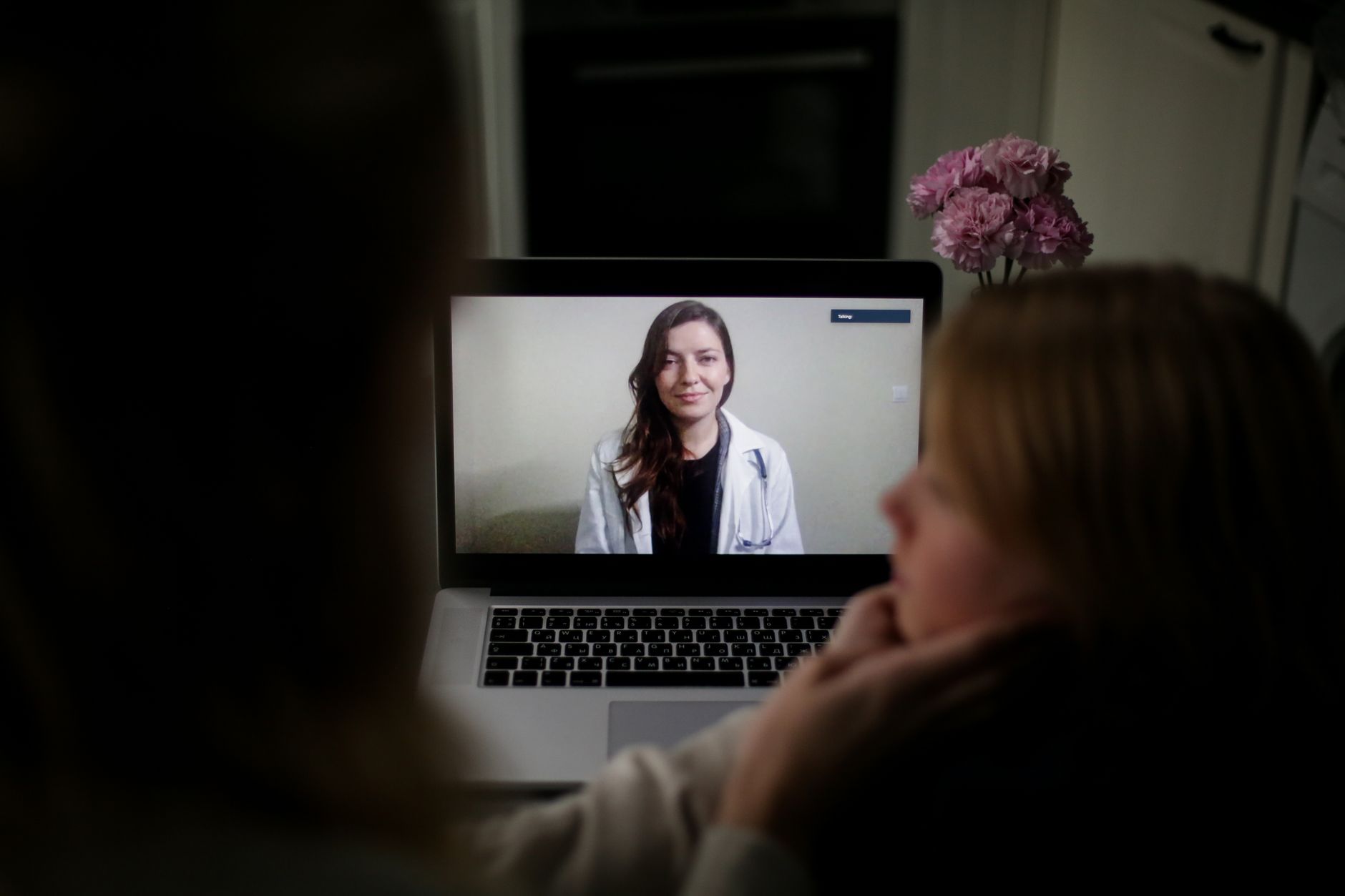 A woman at home talks with a smiling doctor on a laptop video call